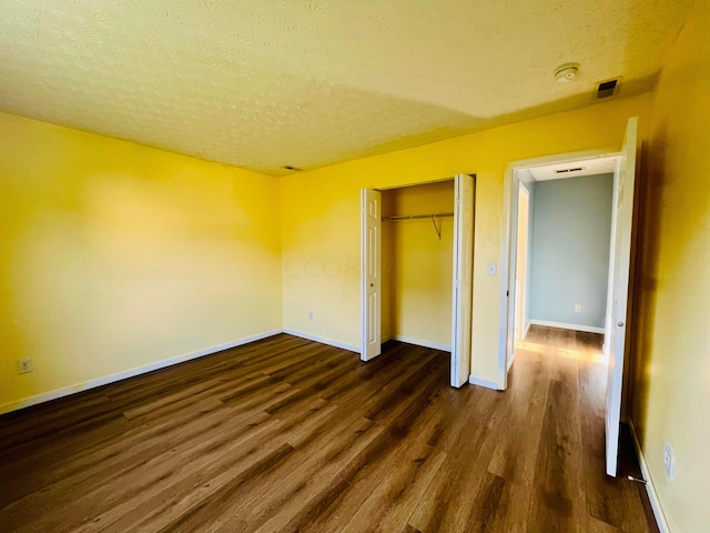 unfurnished bedroom with dark hardwood / wood-style flooring, a textured ceiling, and a closet