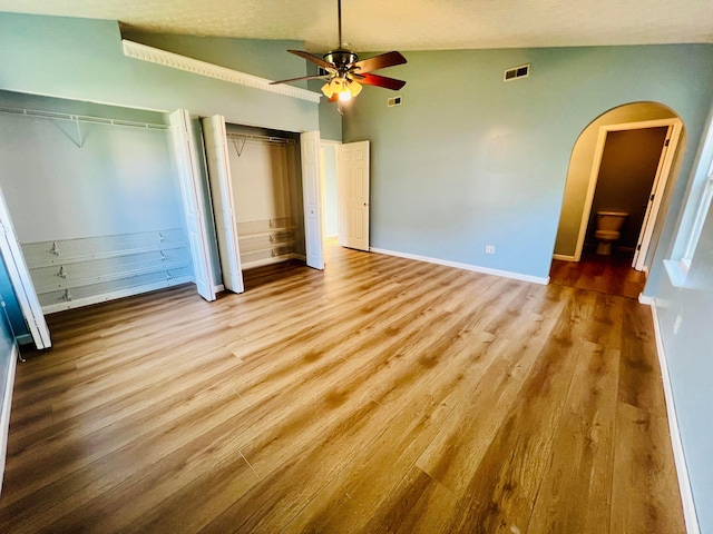 unfurnished bedroom featuring light hardwood / wood-style flooring, vaulted ceiling, ceiling fan, and ensuite bathroom