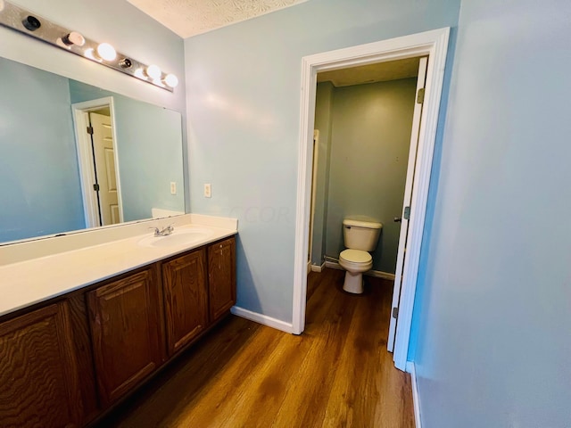 bathroom featuring vanity, hardwood / wood-style floors, a textured ceiling, and toilet