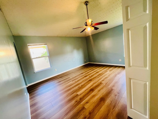 spare room featuring hardwood / wood-style flooring, ceiling fan, lofted ceiling, and a textured ceiling