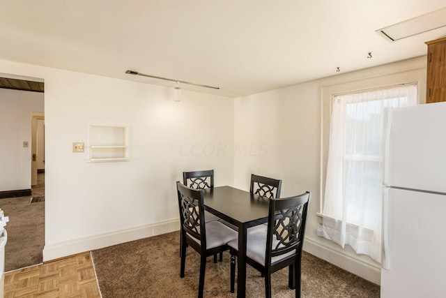 dining space with track lighting and parquet flooring