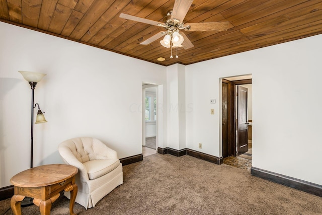 living area featuring ceiling fan, dark carpet, and wooden ceiling