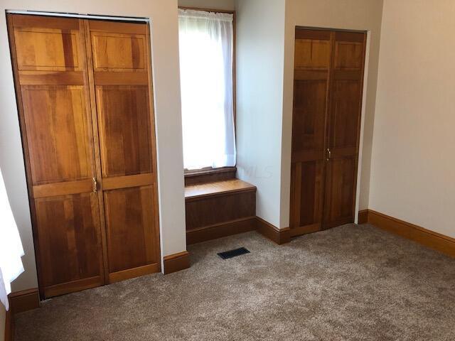 unfurnished bedroom with dark carpet and multiple windows