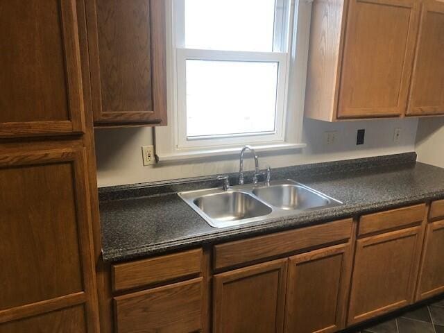 kitchen with dark tile patterned flooring, a healthy amount of sunlight, and sink