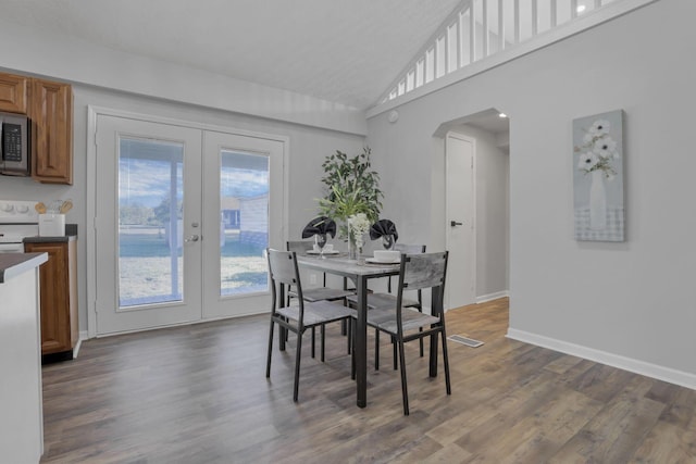 dining space featuring dark hardwood / wood-style flooring, high vaulted ceiling, and french doors