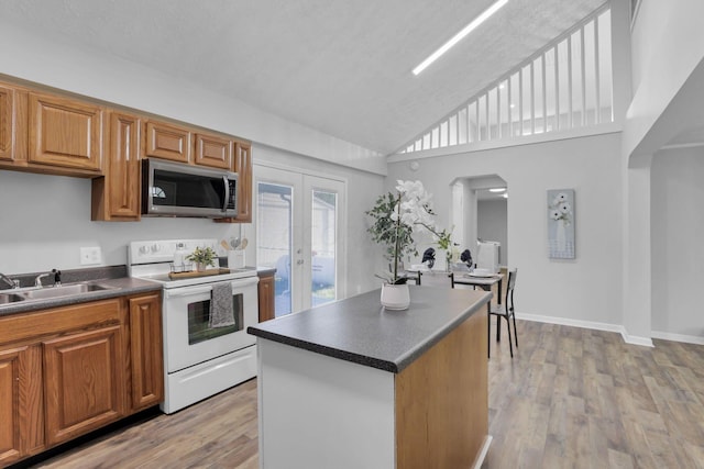 kitchen with high vaulted ceiling, french doors, sink, electric range, and light wood-type flooring