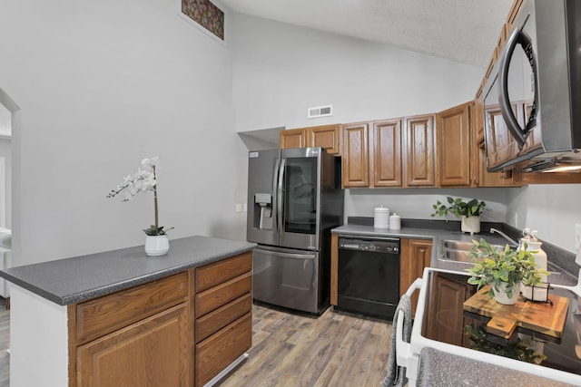 kitchen featuring a textured ceiling, light wood-type flooring, stainless steel appliances, and high vaulted ceiling