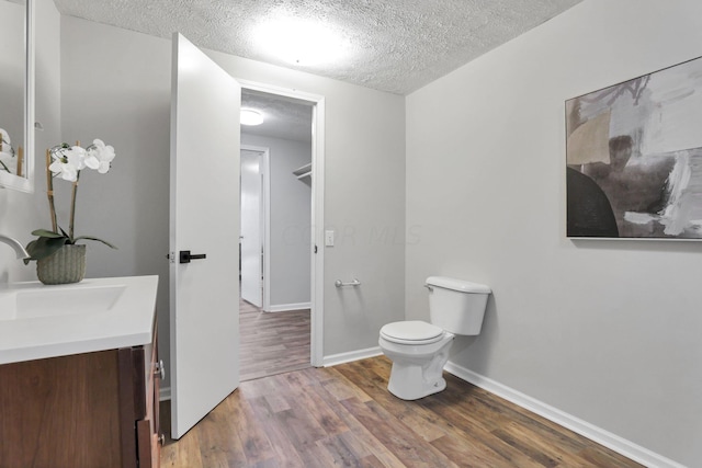 bathroom featuring vanity, wood-type flooring, a textured ceiling, and toilet