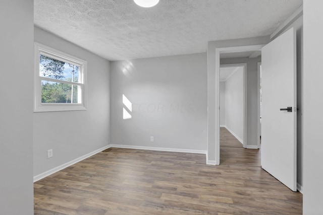 empty room featuring dark hardwood / wood-style flooring and a textured ceiling