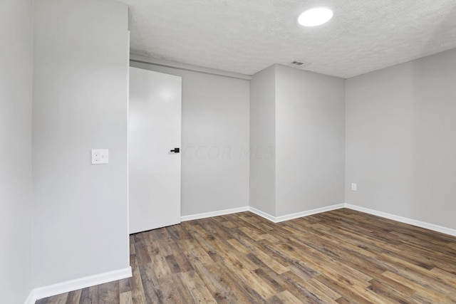 unfurnished room with a textured ceiling and dark hardwood / wood-style floors