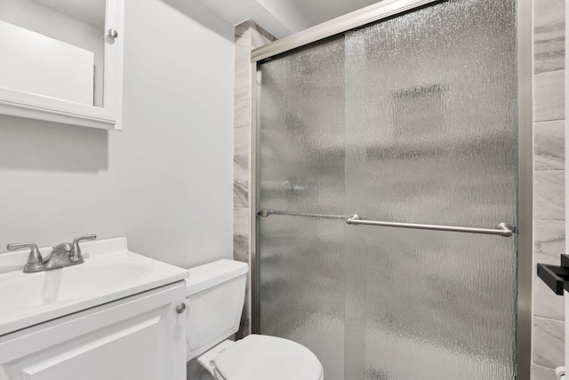 bathroom with vanity, toilet, and a shower with door