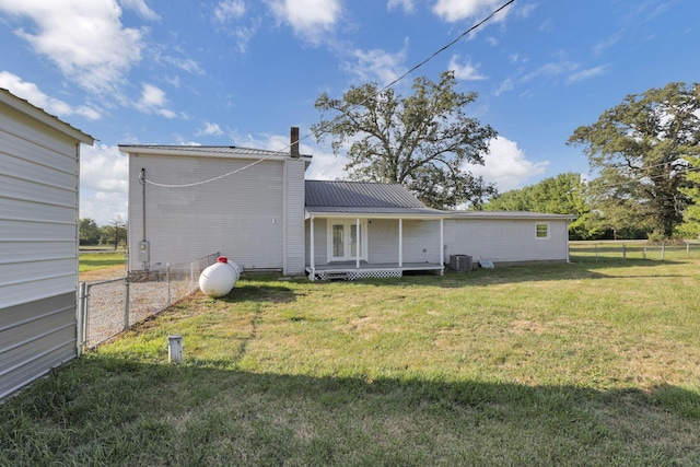 back of property featuring a lawn and central AC