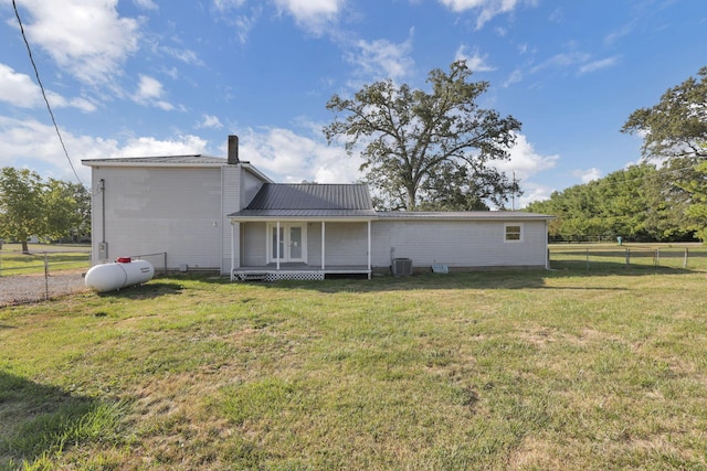 rear view of property with a lawn and central air condition unit