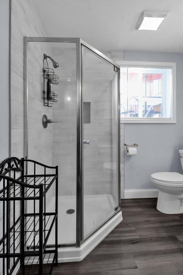 bathroom with wood-type flooring, toilet, and a shower with shower door