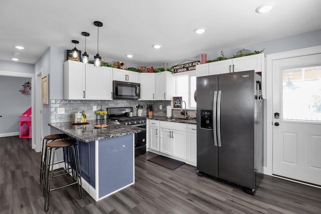 kitchen with sink, white cabinetry, black appliances, decorative light fixtures, and kitchen peninsula