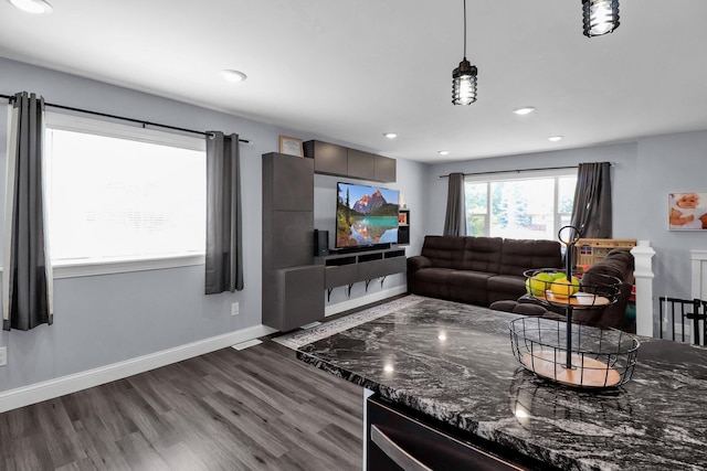 kitchen with hanging light fixtures, dark brown cabinets, dark hardwood / wood-style floors, and dark stone countertops