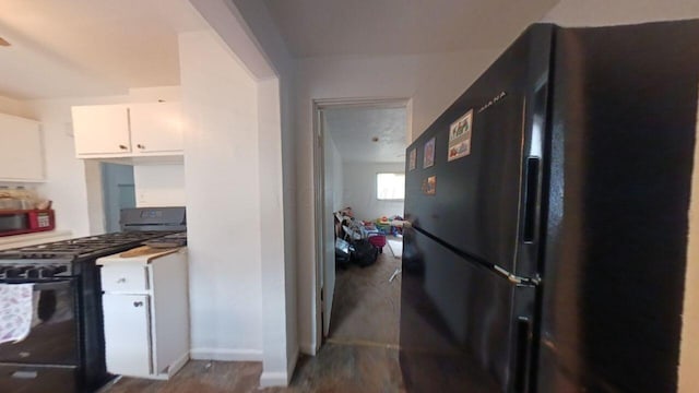 kitchen with black appliances, white cabinets, and hardwood / wood-style flooring