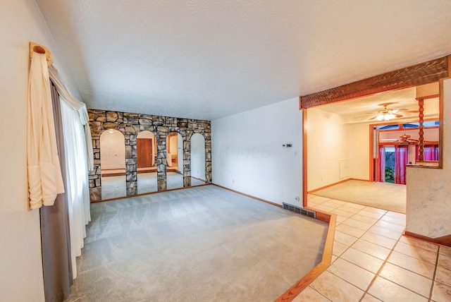 empty room with ceiling fan, light tile patterned floors, and a textured ceiling