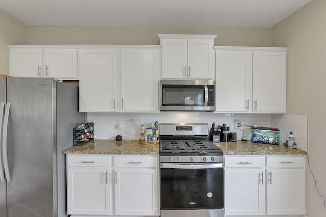 kitchen with white cabinets, decorative backsplash, light stone countertops, and appliances with stainless steel finishes