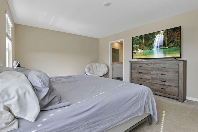 bedroom featuring light carpet and connected bathroom