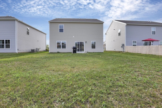 rear view of house with a yard and central AC unit