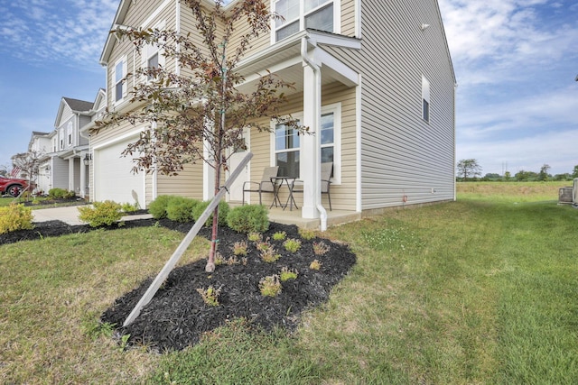 view of property exterior featuring a lawn, a garage, and covered porch