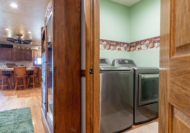 washroom with separate washer and dryer, ceiling fan, light hardwood / wood-style flooring, and a textured ceiling