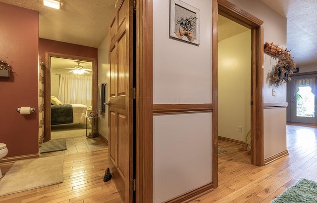 hallway with light wood-type flooring and a textured ceiling