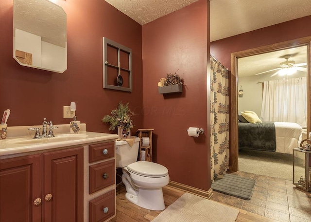 bathroom featuring vanity, a textured ceiling, ceiling fan, hardwood / wood-style floors, and toilet