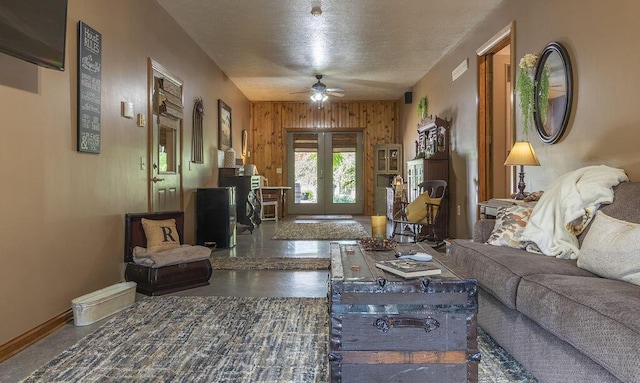 living room featuring french doors, a textured ceiling, ceiling fan, and wooden walls