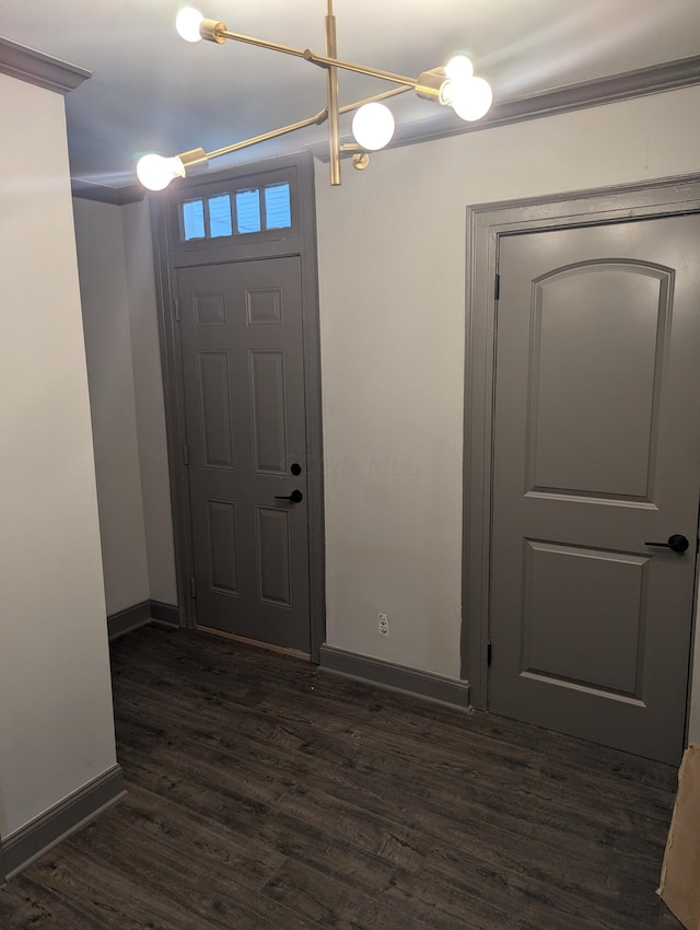 entryway featuring dark hardwood / wood-style floors, ornamental molding, and an inviting chandelier