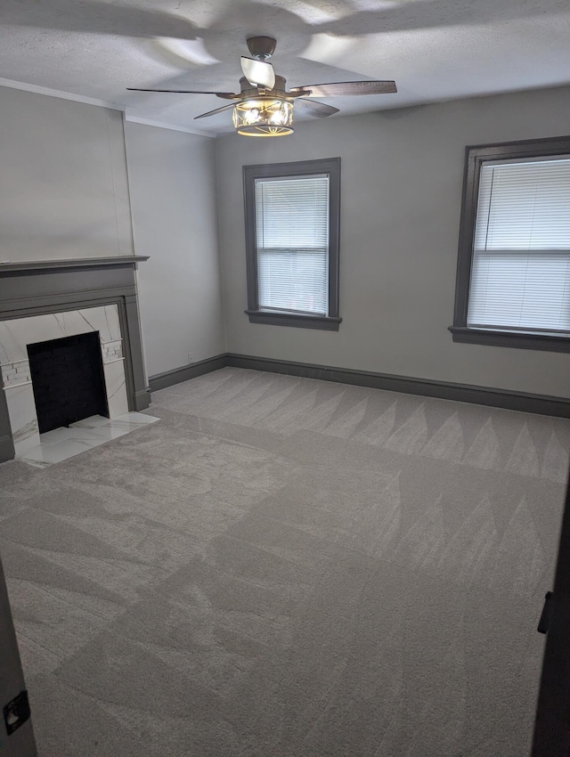 unfurnished living room featuring a premium fireplace, ceiling fan, light carpet, and a textured ceiling