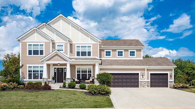 craftsman-style house featuring covered porch, a front yard, and a garage