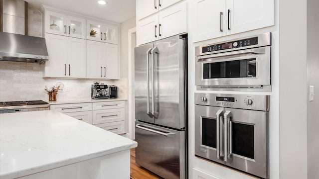 kitchen with white cabinetry, wall chimney range hood, and appliances with stainless steel finishes