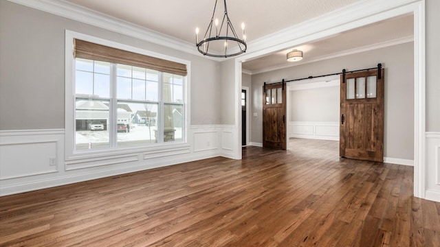 unfurnished dining area with dark hardwood / wood-style floors, a barn door, crown molding, and an inviting chandelier