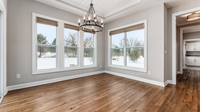 unfurnished dining area featuring dark hardwood / wood-style floors, a tray ceiling, and a notable chandelier