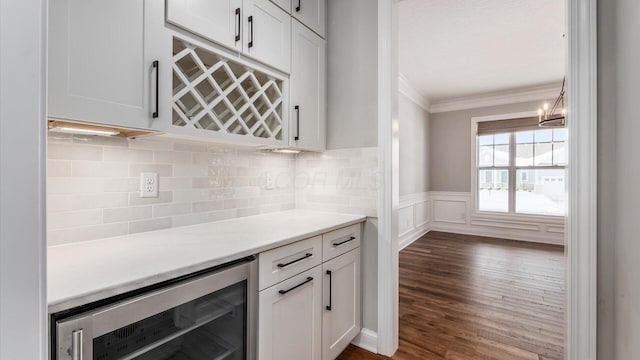 bar featuring wine cooler, crown molding, dark hardwood / wood-style flooring, and white cabinets