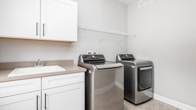 laundry area featuring washer and dryer, cabinets, and sink