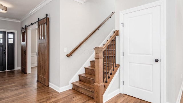 stairs with wood-type flooring, a barn door, and ornamental molding