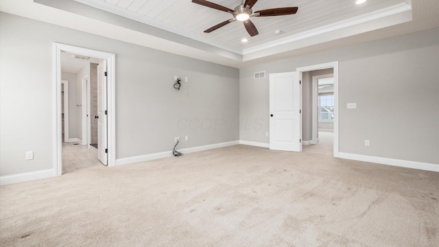 carpeted empty room featuring ceiling fan, a raised ceiling, ornamental molding, and wooden ceiling