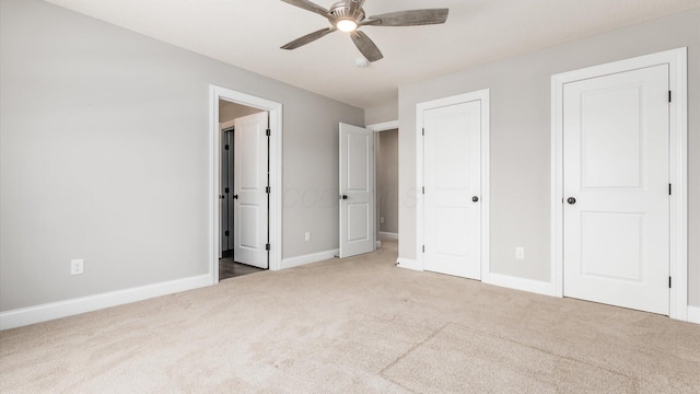 unfurnished bedroom with ceiling fan, carpet, and two closets