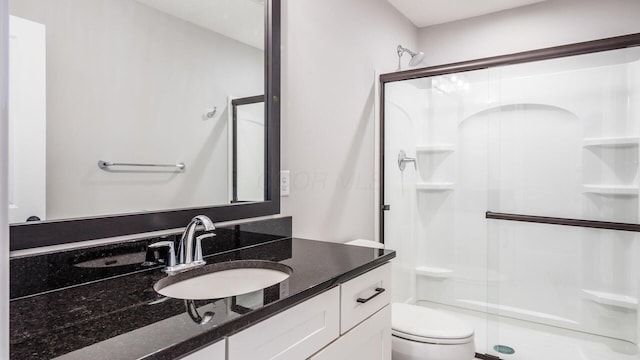 bathroom with vanity, toilet, and a shower with shower door