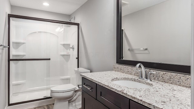 bathroom featuring hardwood / wood-style flooring, toilet, an enclosed shower, and vanity