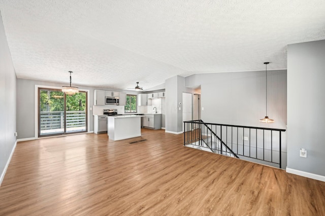 unfurnished living room with lofted ceiling, light hardwood / wood-style floors, and a healthy amount of sunlight