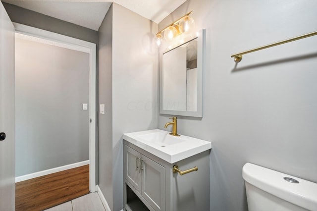 bathroom featuring toilet, vanity, and hardwood / wood-style flooring