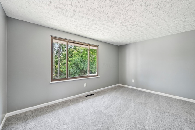 carpeted empty room featuring a textured ceiling