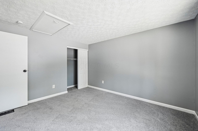 unfurnished bedroom featuring a textured ceiling, carpet floors, and a closet