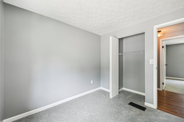 unfurnished bedroom featuring a closet, carpet, and a textured ceiling