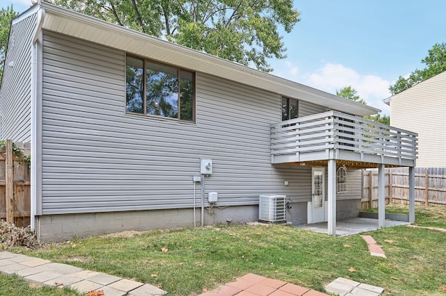 exterior space with a lawn, a patio area, central air condition unit, and a wooden deck