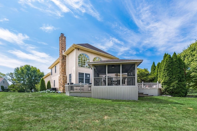 rear view of house featuring a sunroom, a wooden deck, and a lawn